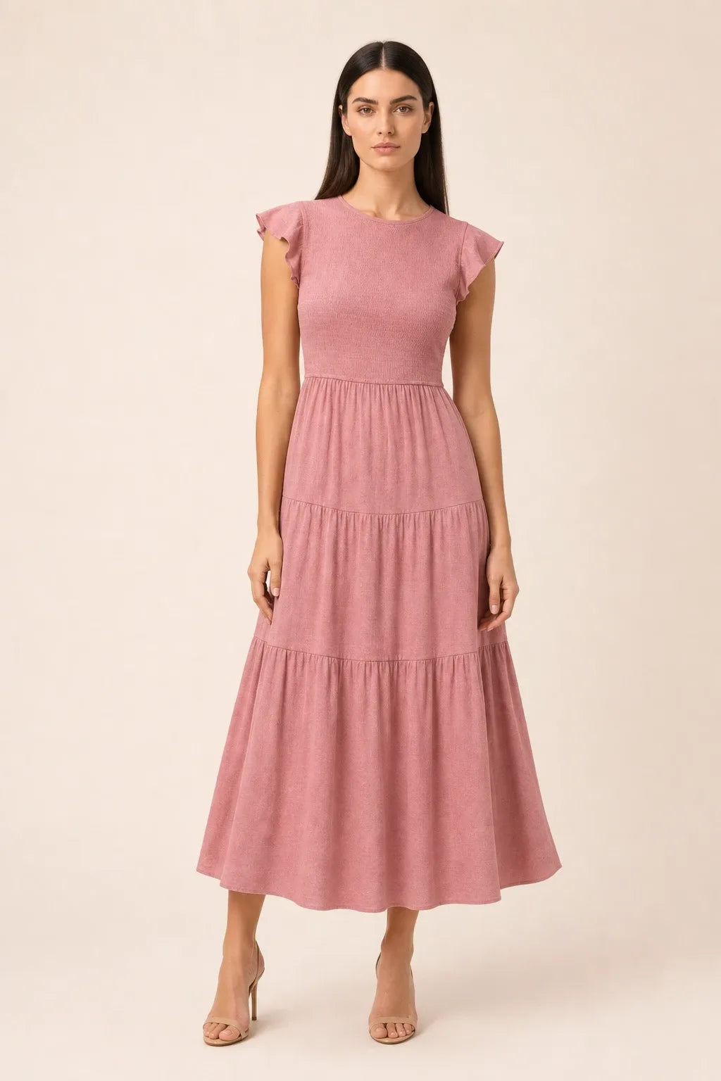 Pink smocked tiered midi dress on model in contrapposto stance