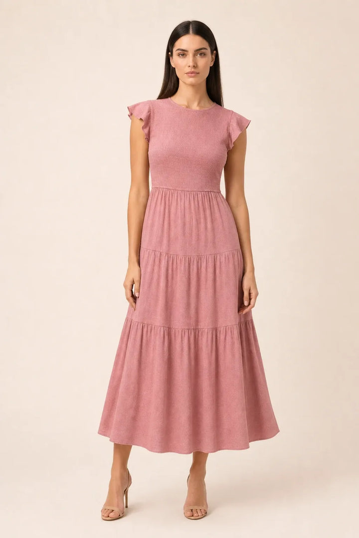 Pink smocked tiered midi dress on model in contrapposto stance