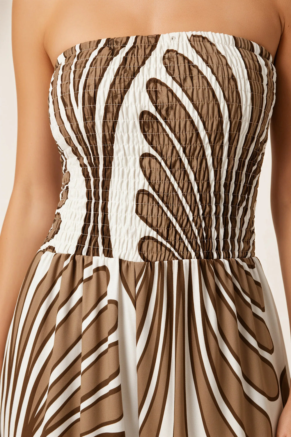 Close-up detail of brown smocked print jumpsuit fabric and construction