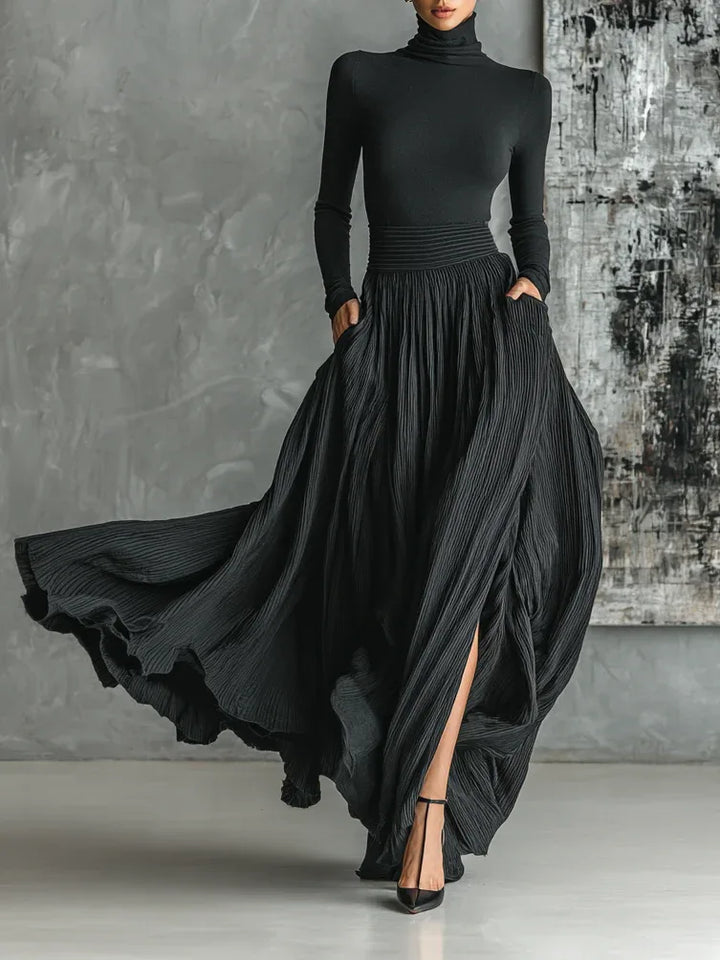 Woman facing forward in a black pleated maxi skirt set with a fitted top