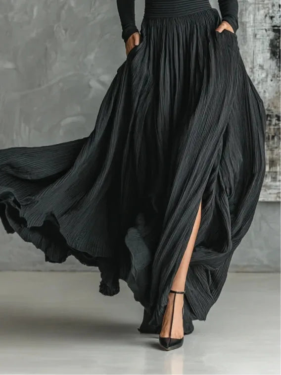 Woman in side profile wearing a black pleated maxi skirt set with a fitted top