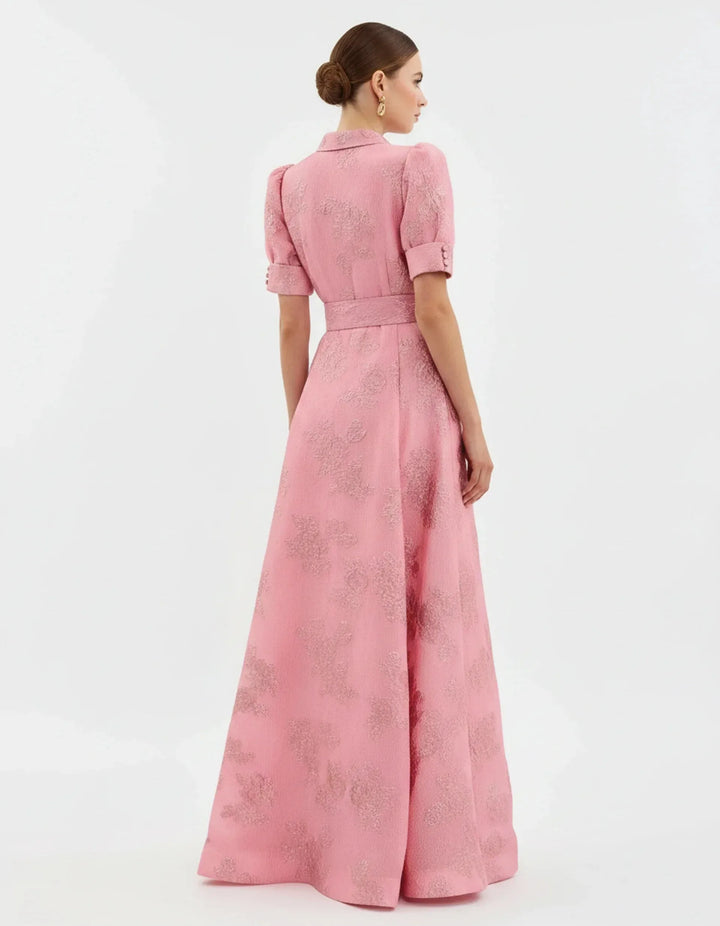 Woman in side profile wearing a beige jacquard maxi gown highlighting the length