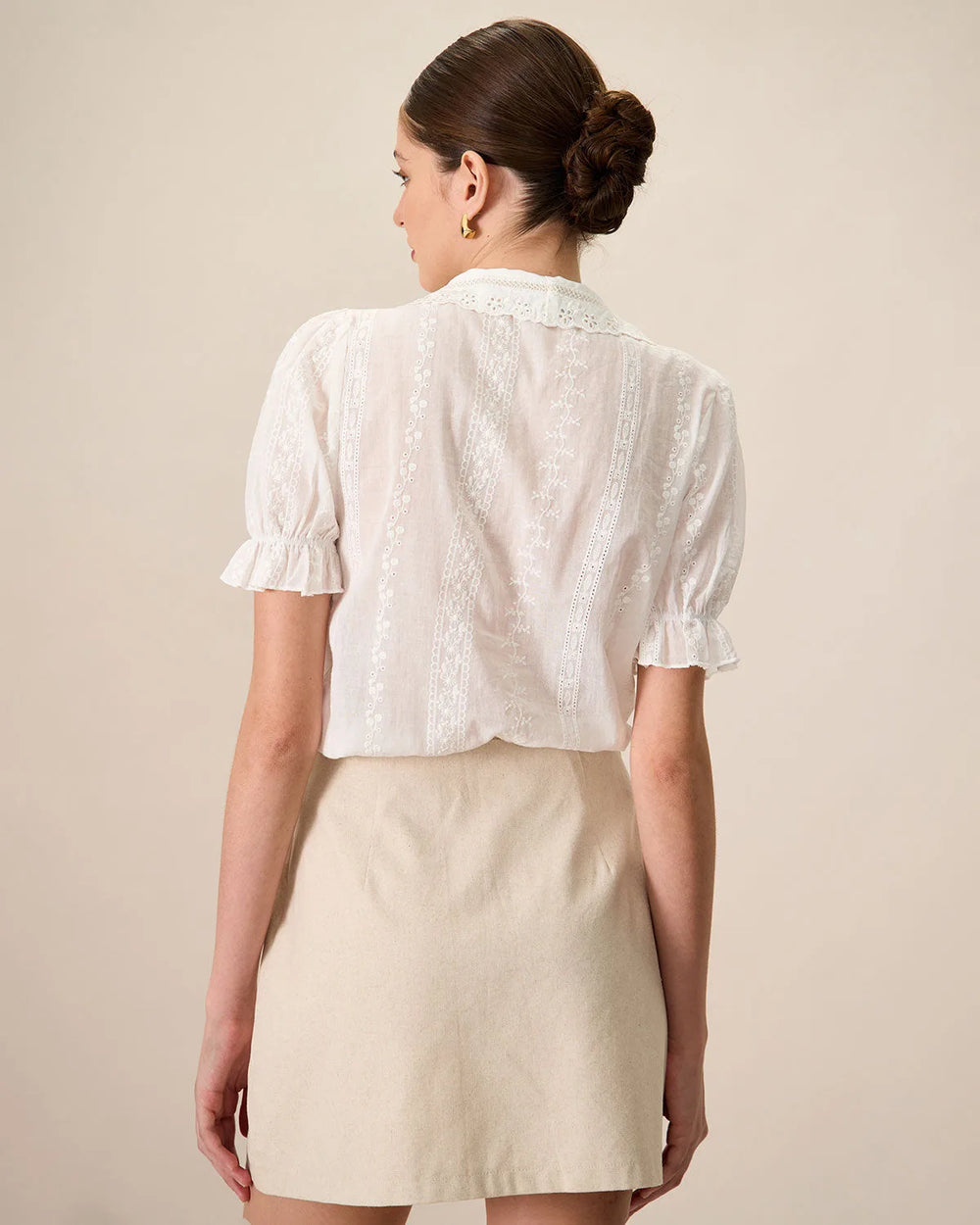 Close-up of white broderie anglaise blouse showing intricate eyelet embroidery fabric detail