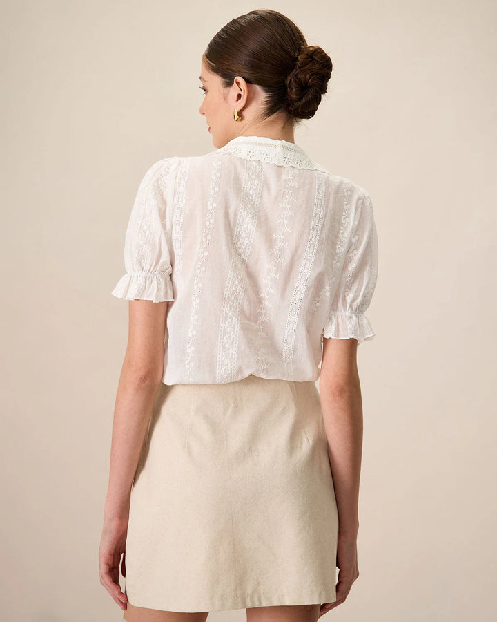 Close-up of white broderie anglaise blouse showing intricate eyelet embroidery fabric detail