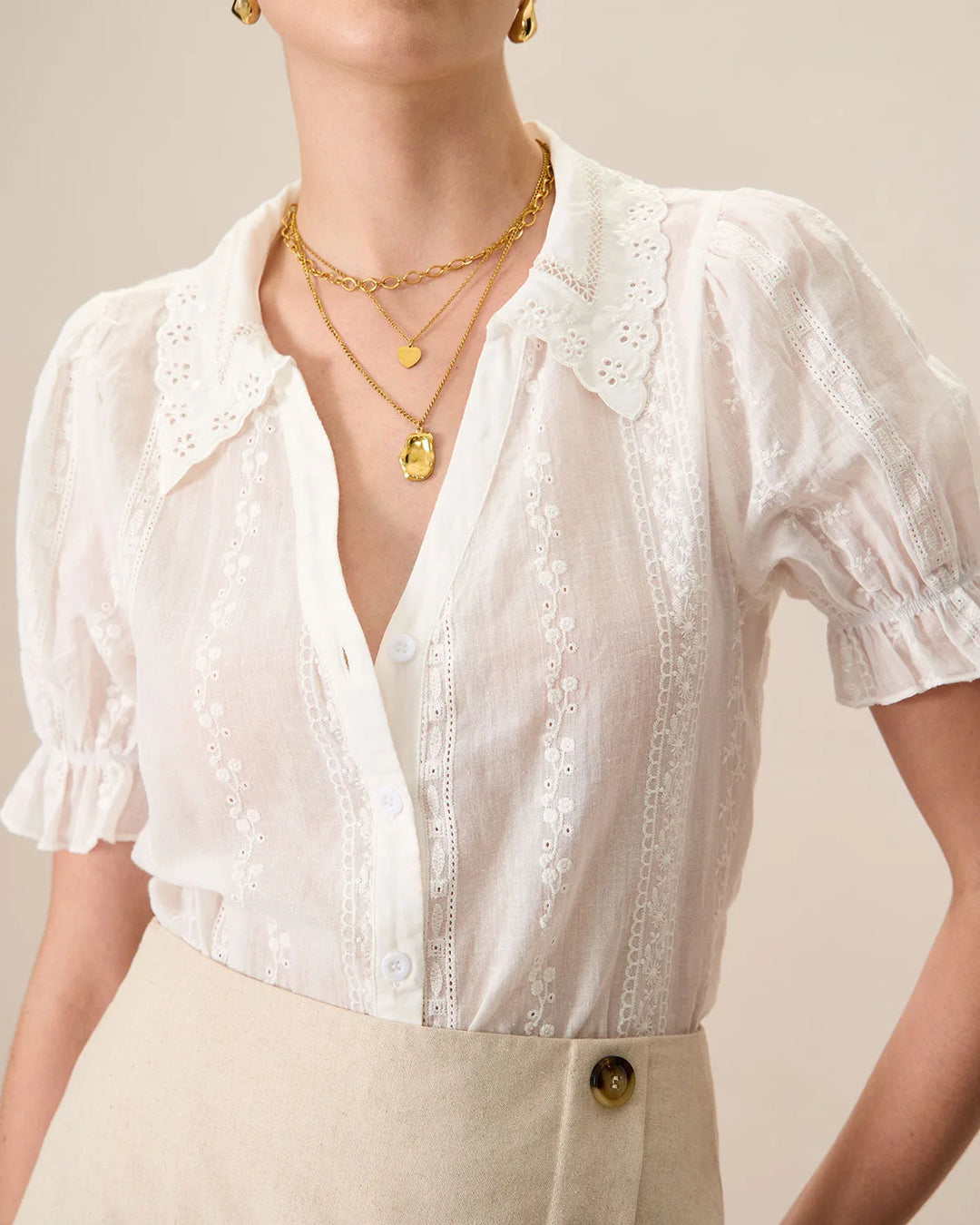 White broderie anglaise blouse on model at three-quarter turn, showing silhouette and sleeve detail
