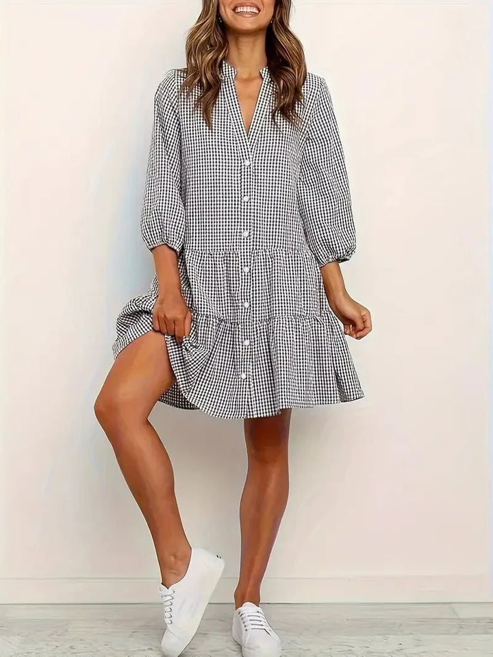 Woman in a black gingham tiered mini dress shown from the side