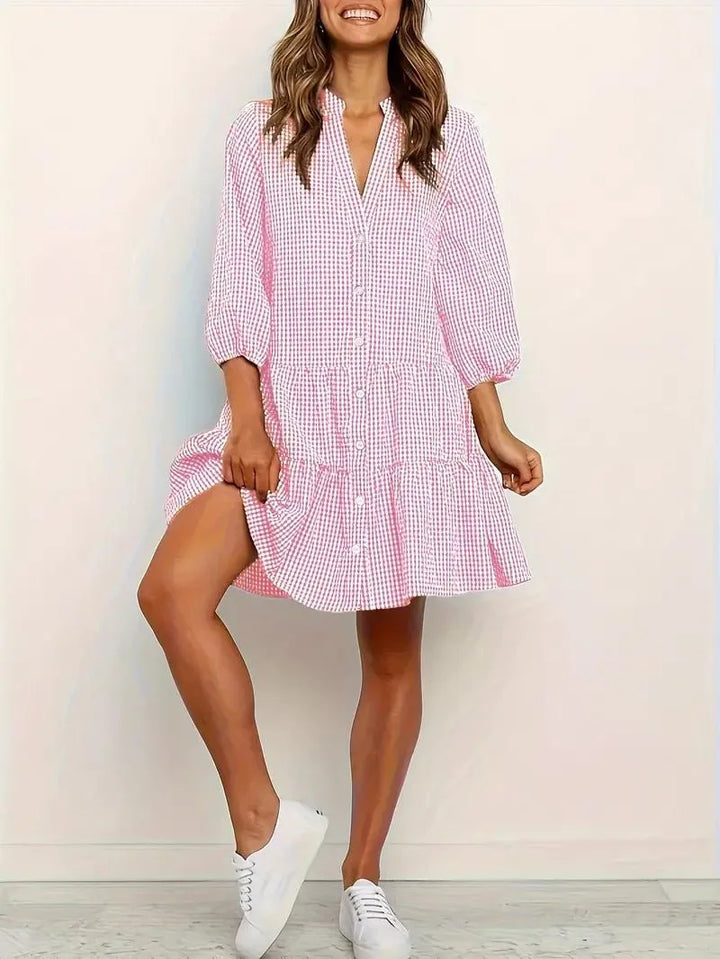 Woman facing forward in a pink gingham tiered mini dress with flutter sleeves