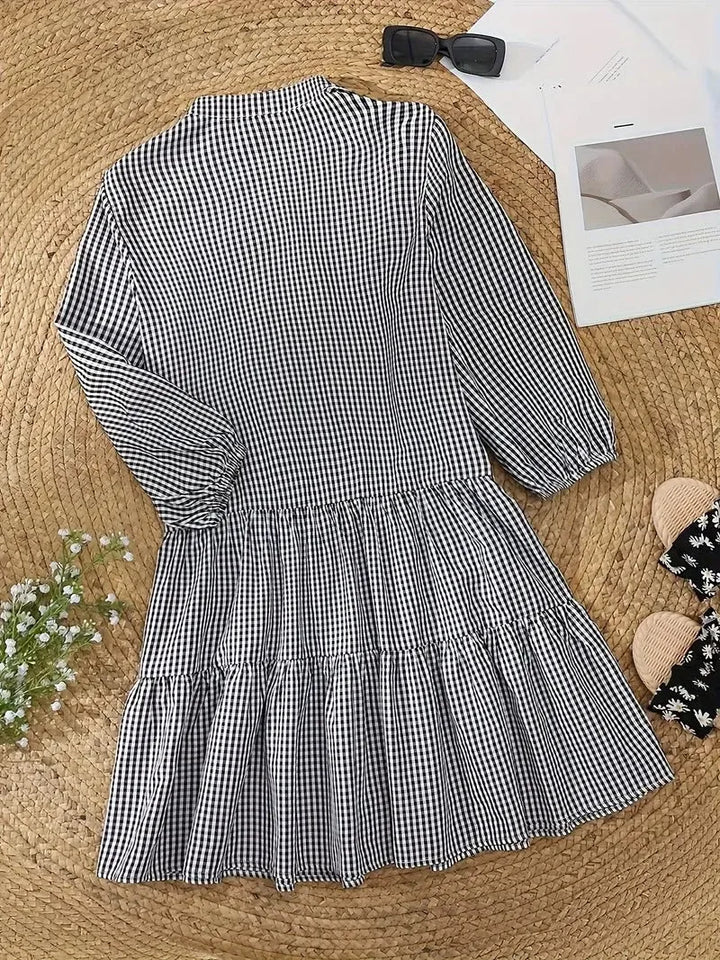Woman wearing a pink gingham tiered mini dress in an alternate styled pose