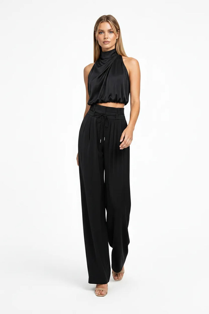Black draped halter top and wide-leg trousers on a model in natural movement
