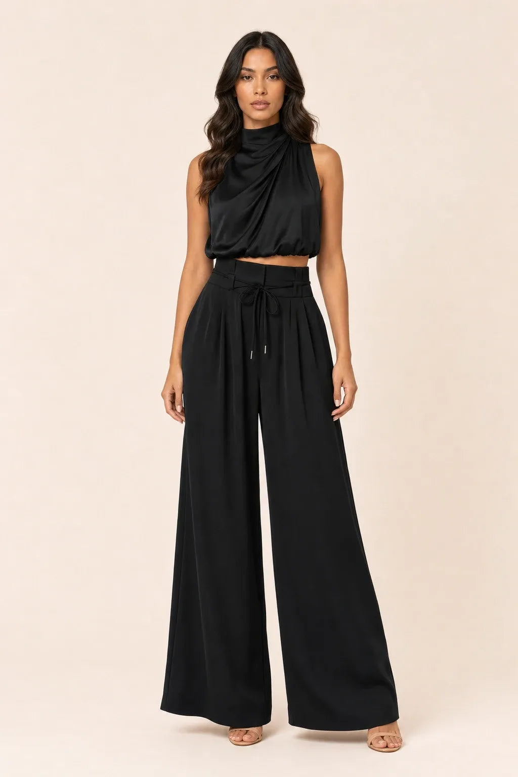 Black draped halter and wide-leg trousers on a model in a contrapposto stance