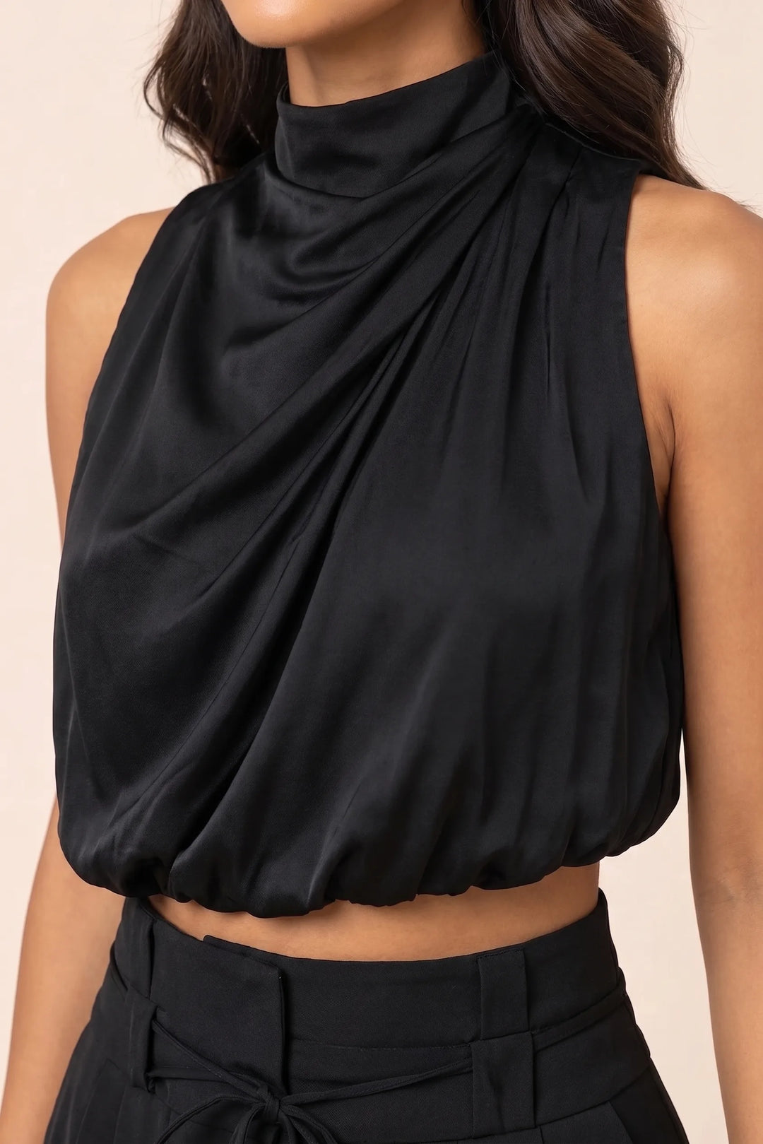 Close-up detail of a black draped halter neckline and fabric drape