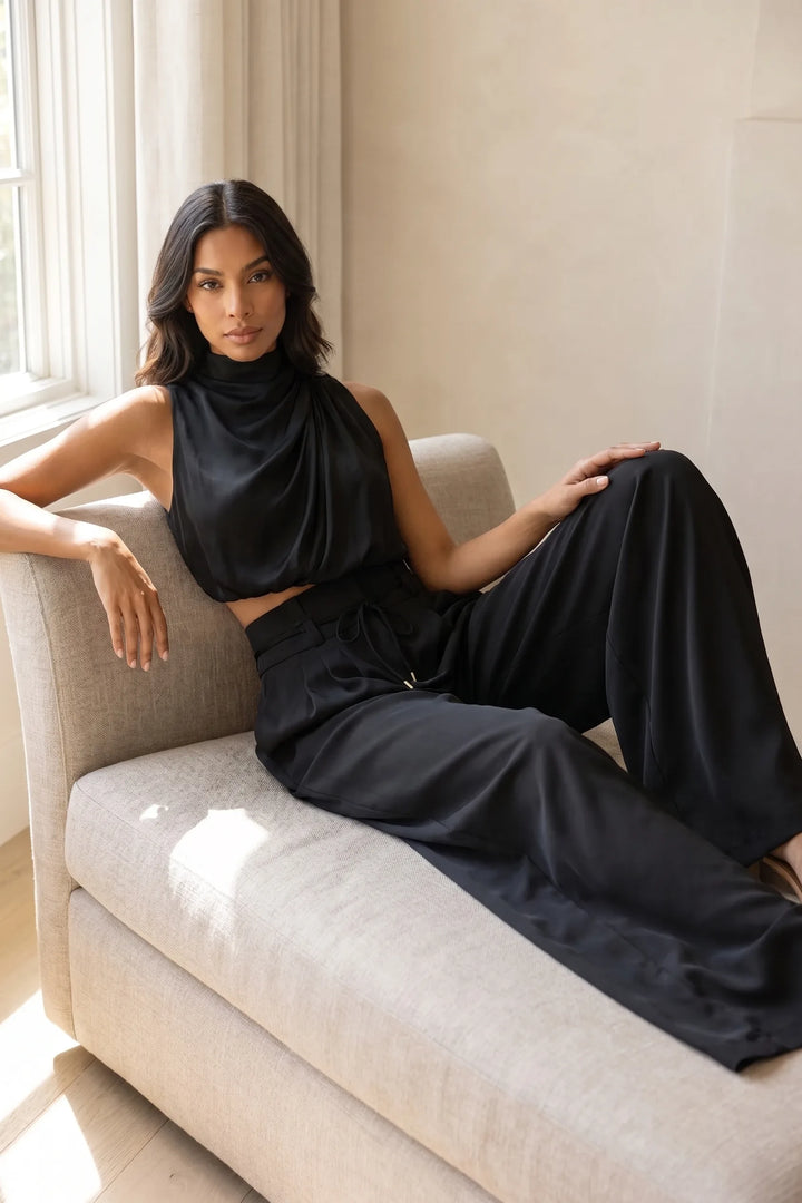 Model in a black draped halter and wide-leg trouser set captured in a candid lifestyle moment