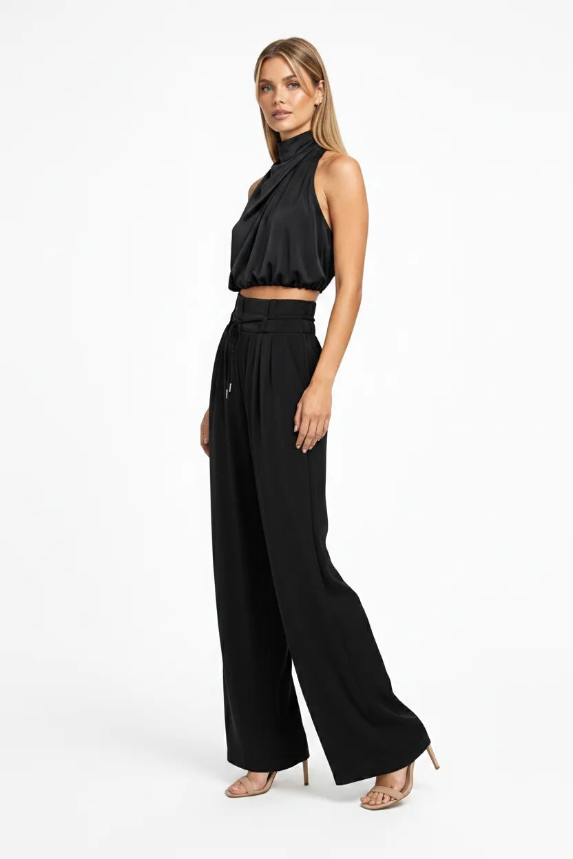 Black draped halter top and wide-leg trousers on a model in a three-quarter turn