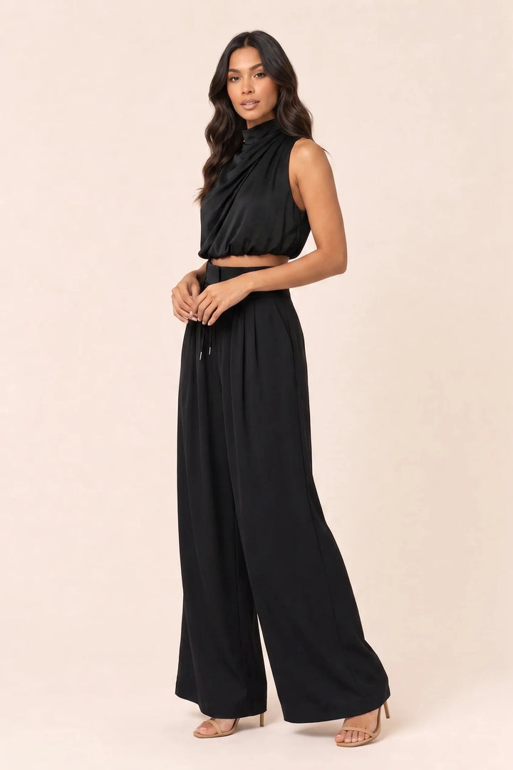 Black draped halter and wide-leg trousers on a model in a three-quarter turn