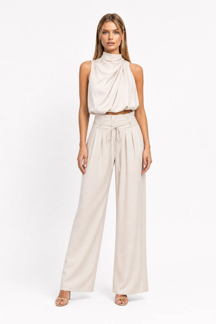 Champagne draped halter top and wide-leg trousers on a model in a contrapposto stance