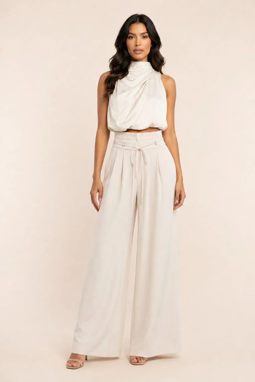 Champagne draped halter and wide-leg trousers on a model in a contrapposto stance