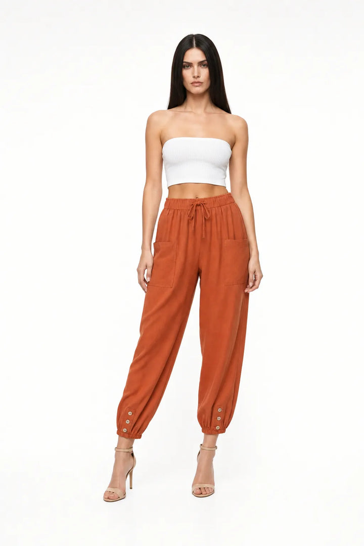 Brick red drawstring jogger pants on a model in a contrapposto stance