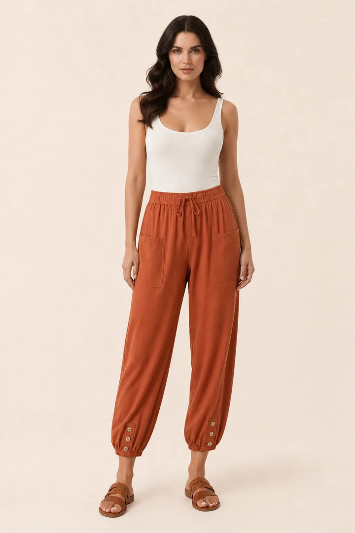 Brick red drawstring jogger pants on a model in a contrapposto stance