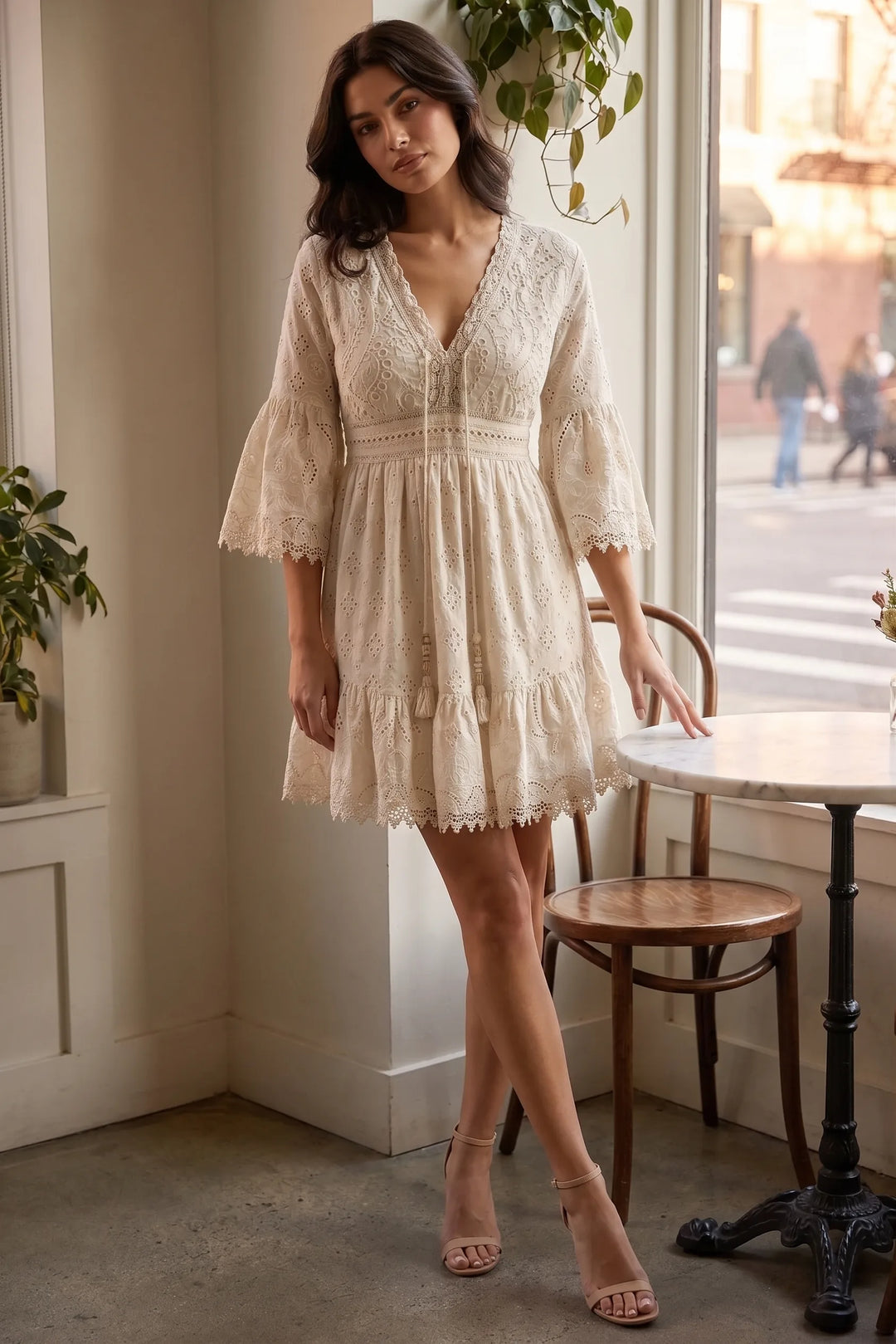Model wearing a light yellow lace eyelet mini dress in a lifestyle setting