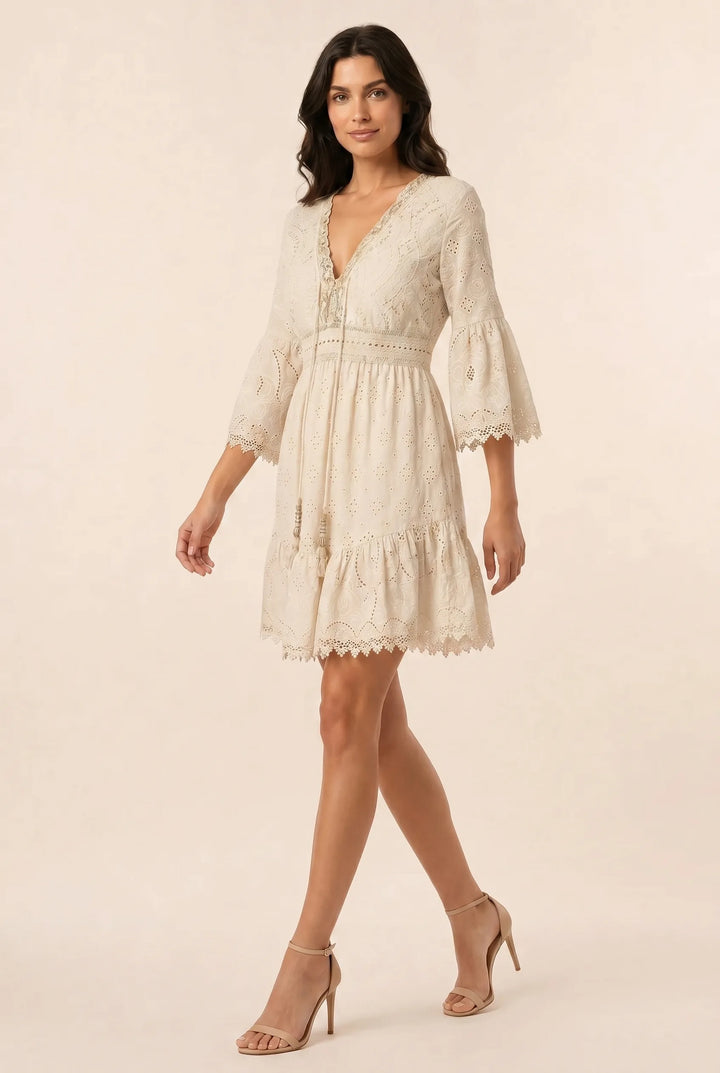 Light yellow lace eyelet mini dress on a model in a three-quarter turn