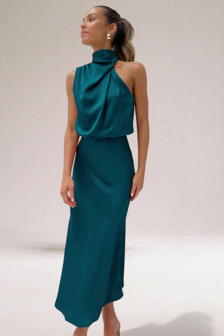 Model in a three-quarter turn wearing an aqua green draped halter midi dress