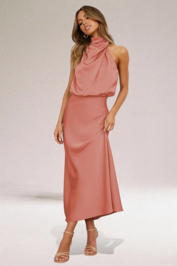 Model in side profile wearing a mauve draped halter midi dress