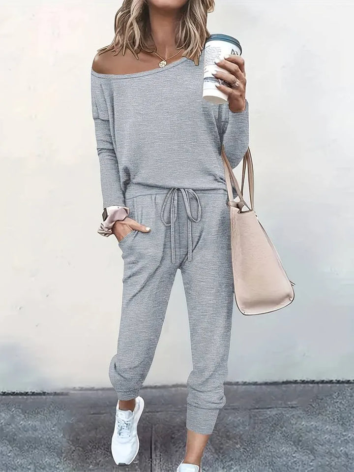 Grey off-shoulder sweatshirt and jogger set worn by a model facing forward