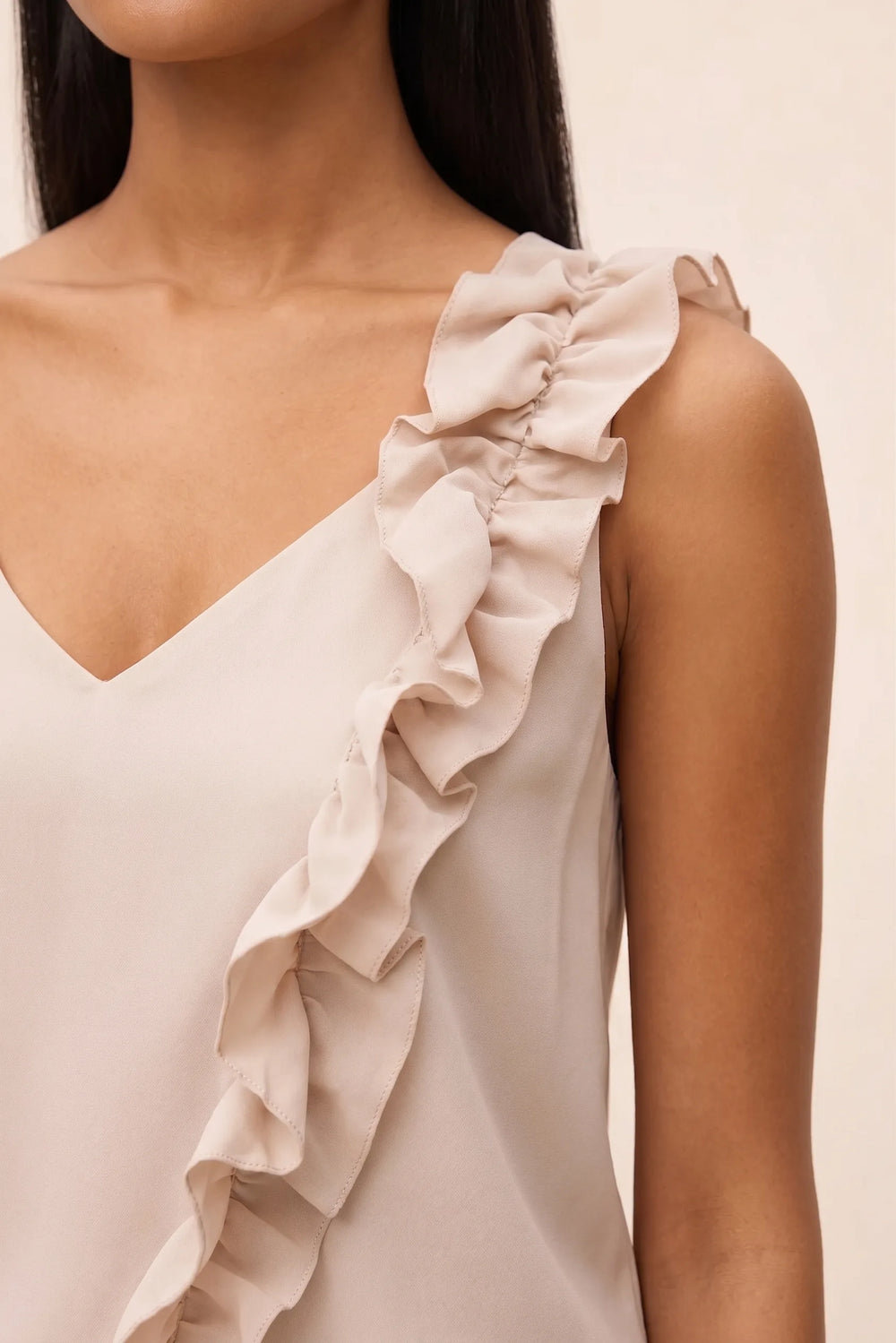 Close-up detail of asymmetric ruffle neckline on beige cami