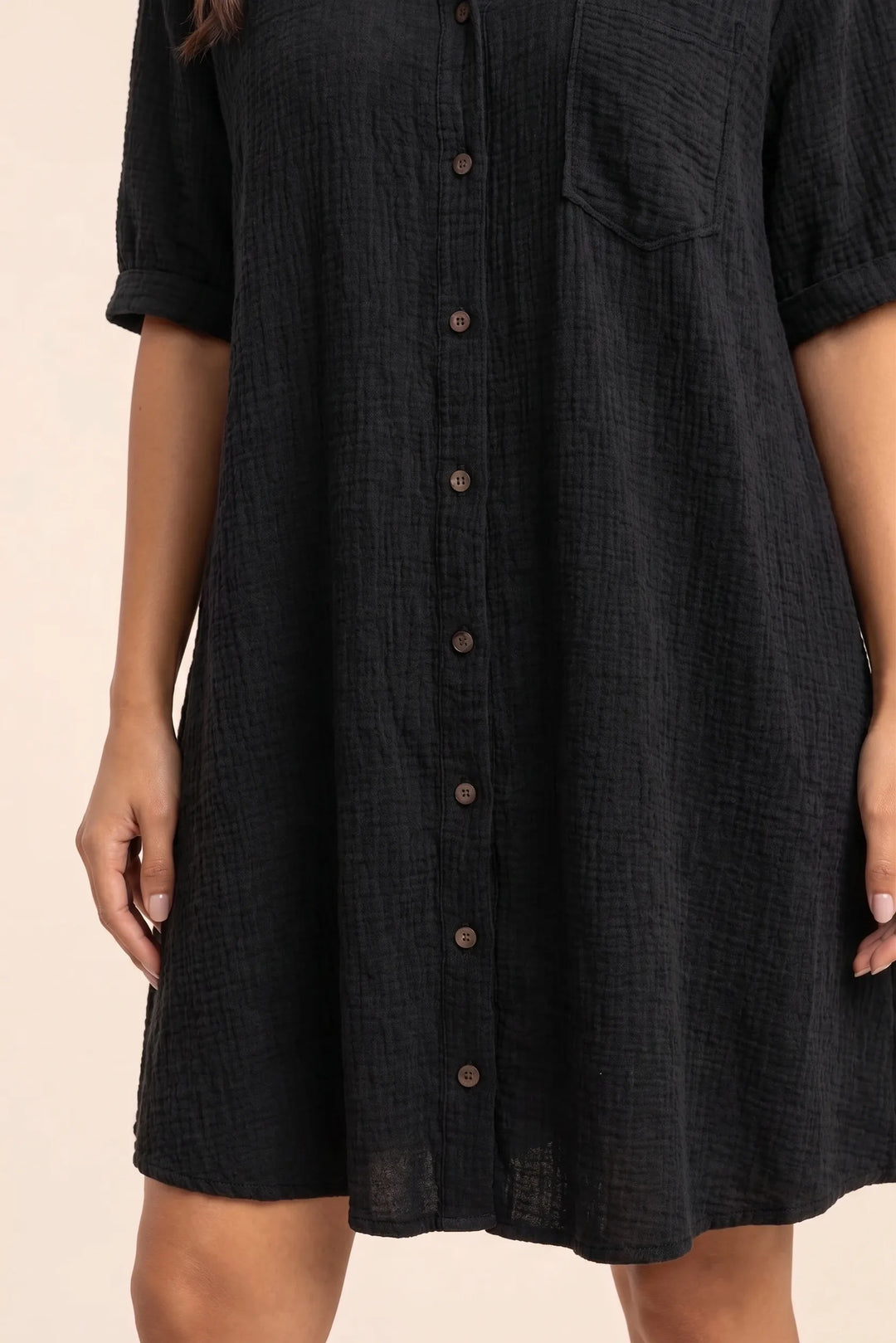 Close-up detail of black gauze shirt dress fabric, buttons, and collar construction