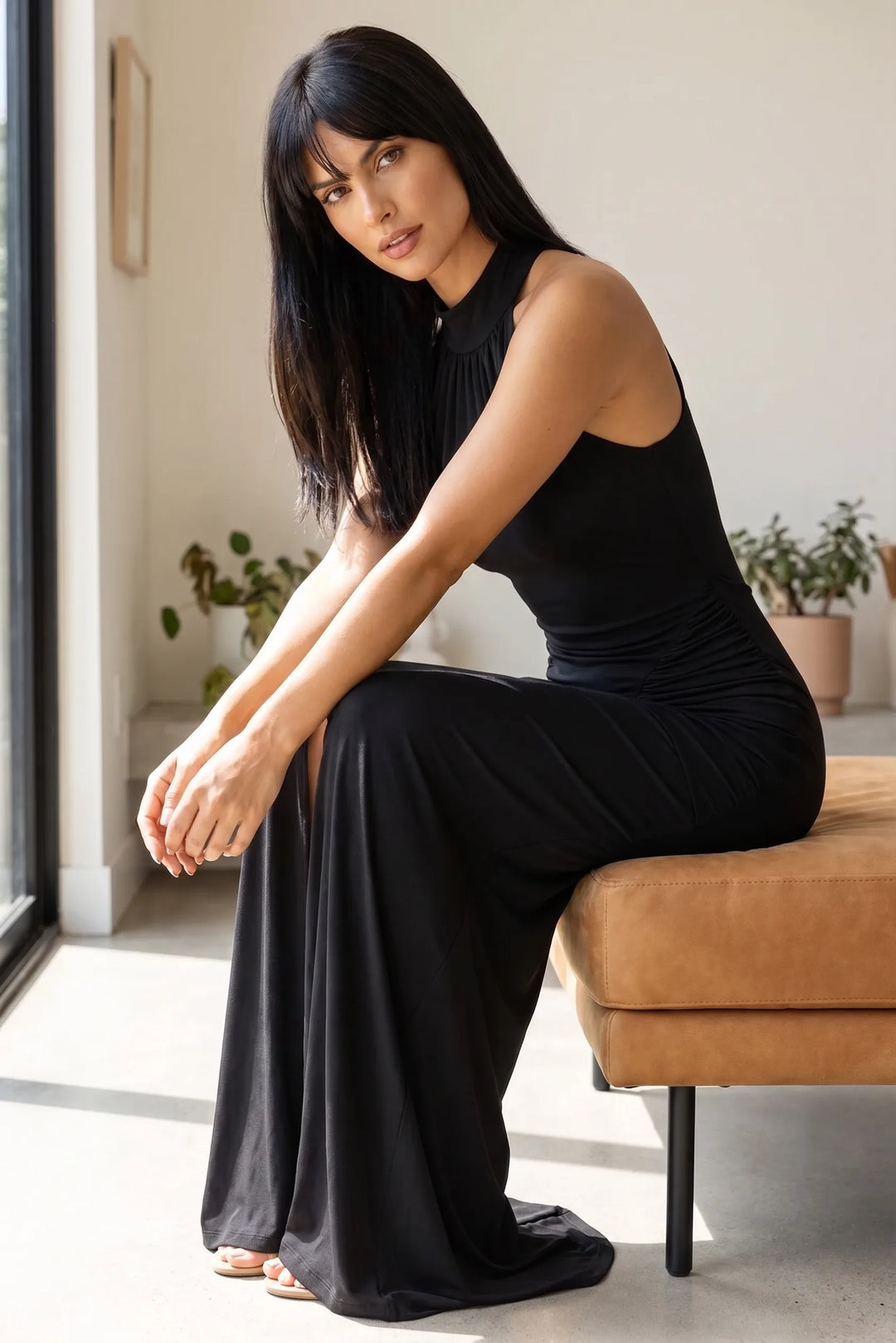 Model wearing black ruched halter gown in second lifestyle scene, full-length view