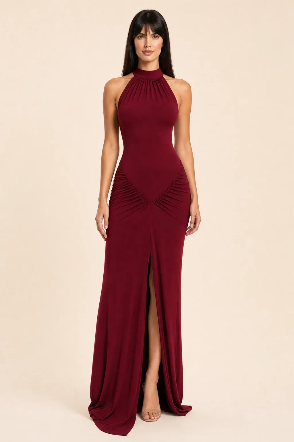 Wine red ruched halter gown on model in contrapposto stance, floor-length silhouette