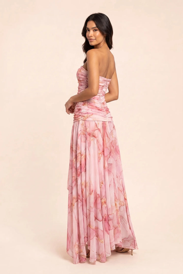 Woman in pink ruched high-low maxi dress, three-quarter turn