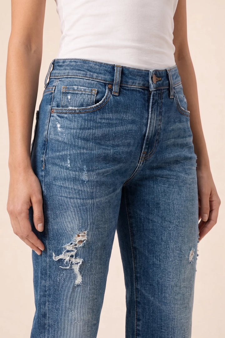 Close-up detail of distressed fabric on dark blue wide leg jeans
