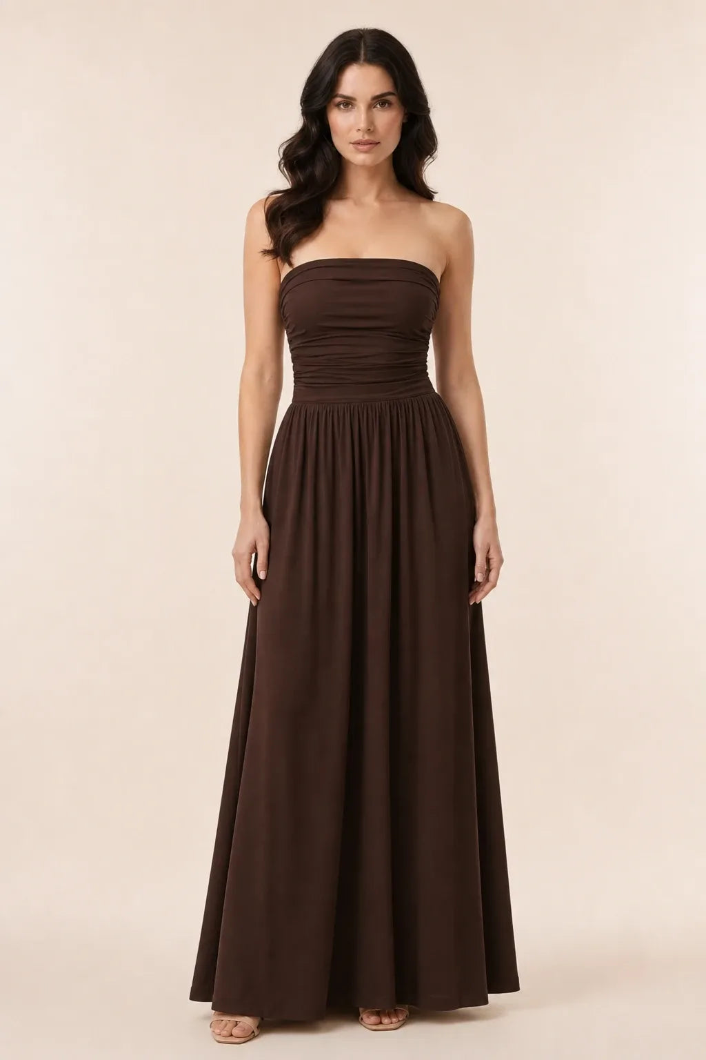 Woman in brown strapless ruched maxi dress standing in contrapposto pose