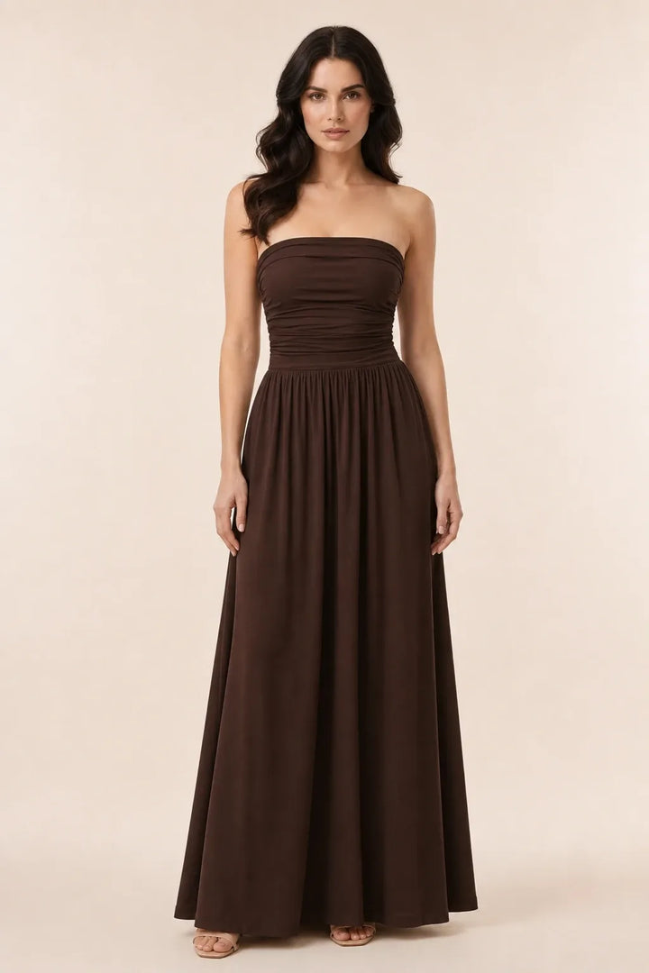 Woman in brown strapless ruched maxi dress standing in contrapposto pose