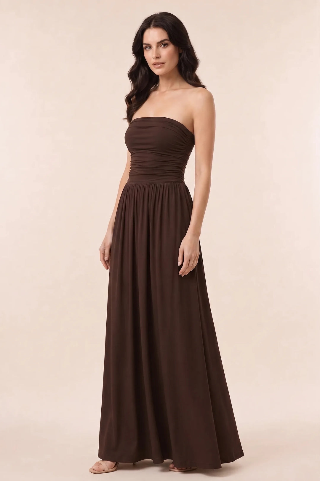 Woman in brown strapless ruched maxi dress in three-quarter turn