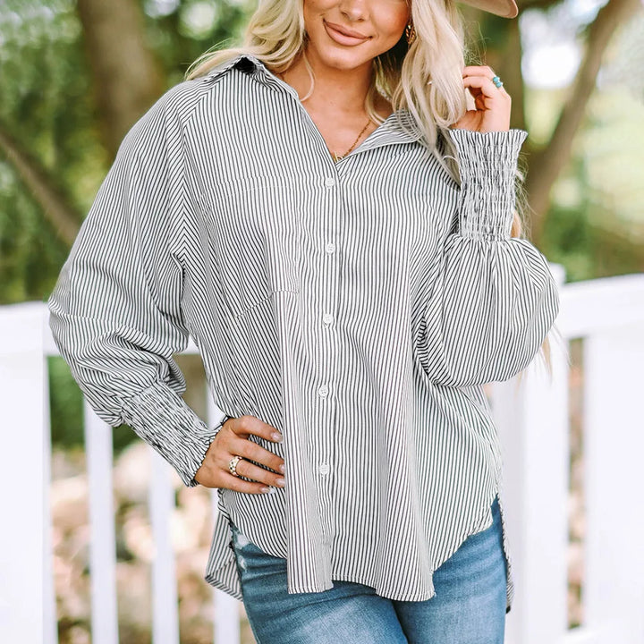 Model at three-quarter turn wearing a gray balloon sleeve blouse with smocked cuffs