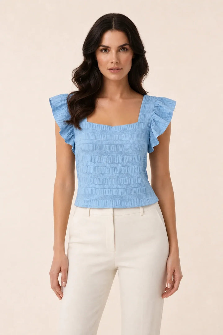 Light blue smocked ruffle sleeve top on model in contrapposto stance