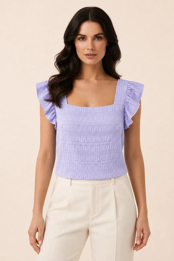 Purple smocked ruffle sleeve top on model in contrapposto stance