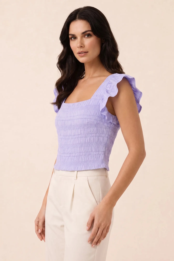 Purple smocked ruffle sleeve top on model in three-quarter turn