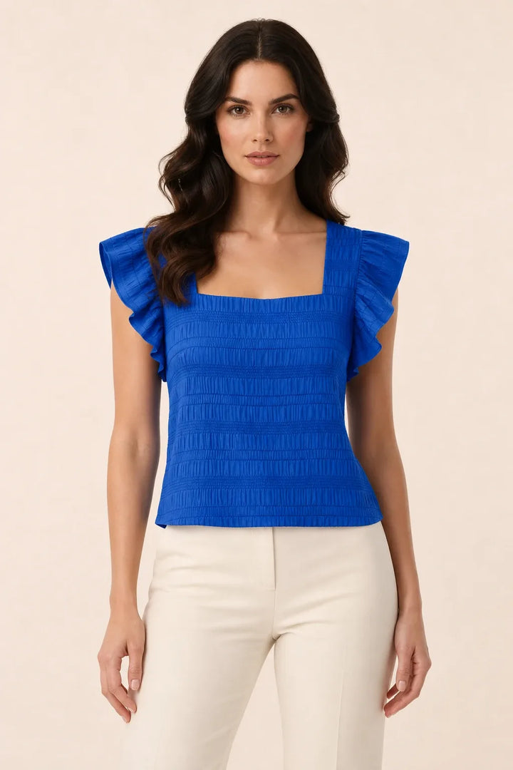 Royal blue smocked ruffle sleeve top on model in contrapposto stance