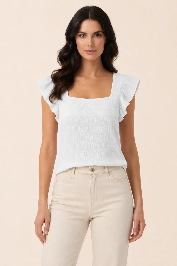 White smocked ruffle sleeve top on model in contrapposto stance