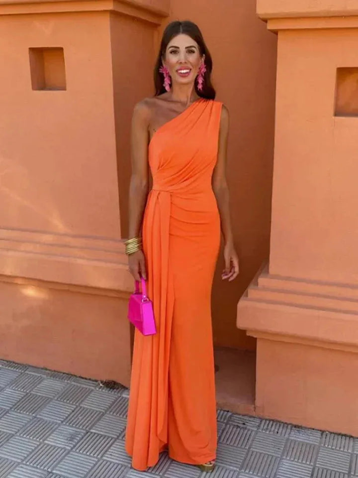 Woman facing forward in a draped orange one-shoulder maxi dress