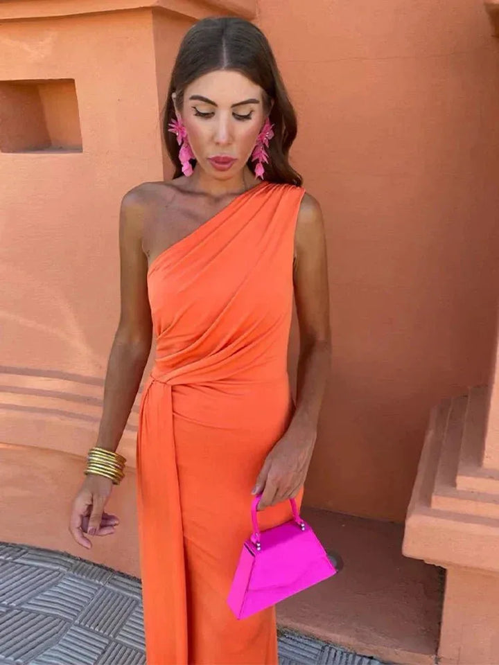 Side view of woman in a draped orange one-shoulder maxi dress