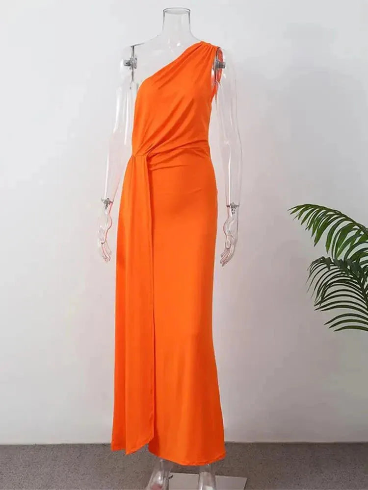 Woman posing in a draped orange one-shoulder maxi dress