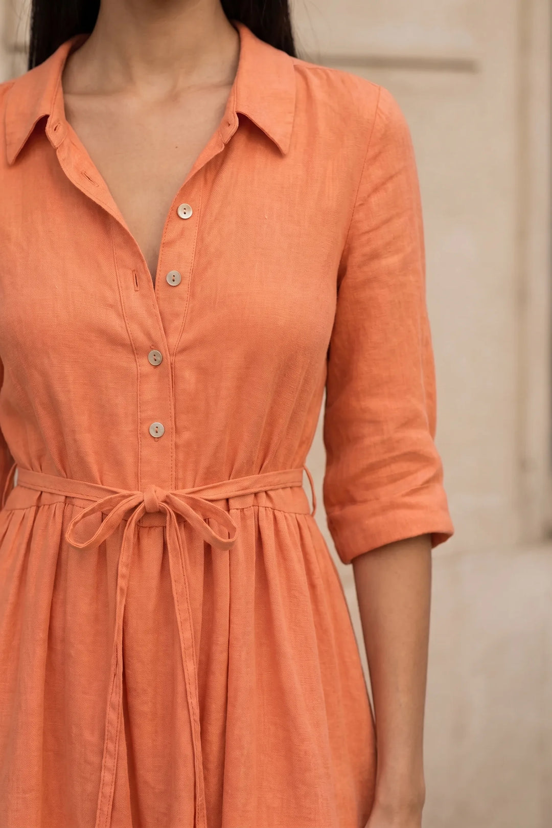 Close-up detail of orange tie waist midi dress showing fabric and waist tie