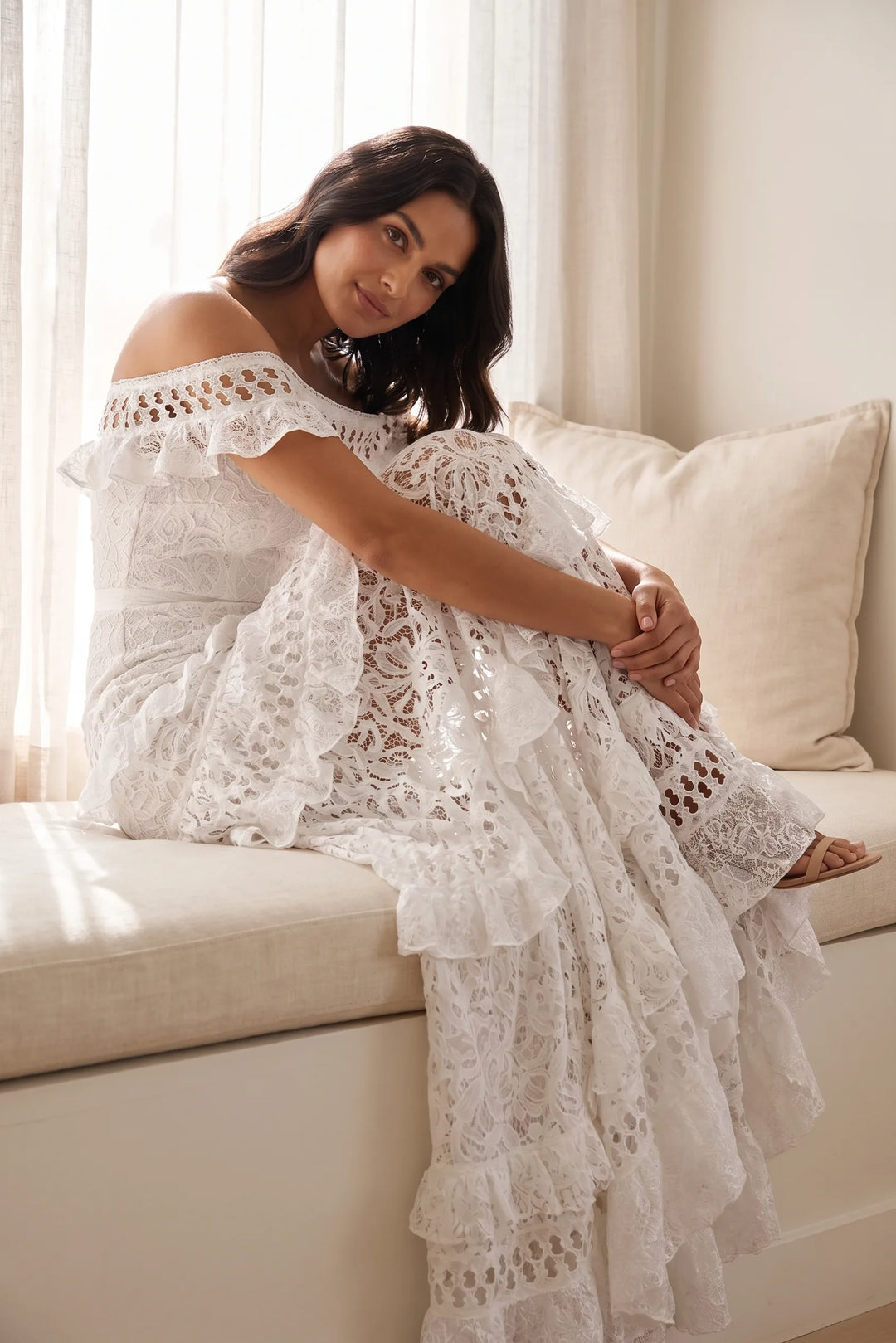 Model in white tiered lace gown captured in candid lifestyle moment, flowing skirt in motion