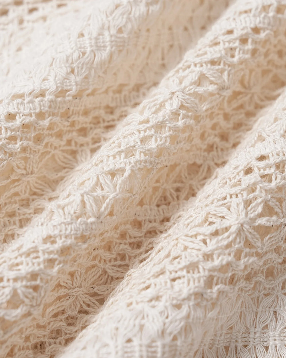 Close-up detail of an apricot crochet blouse showing ruffle neckline texture