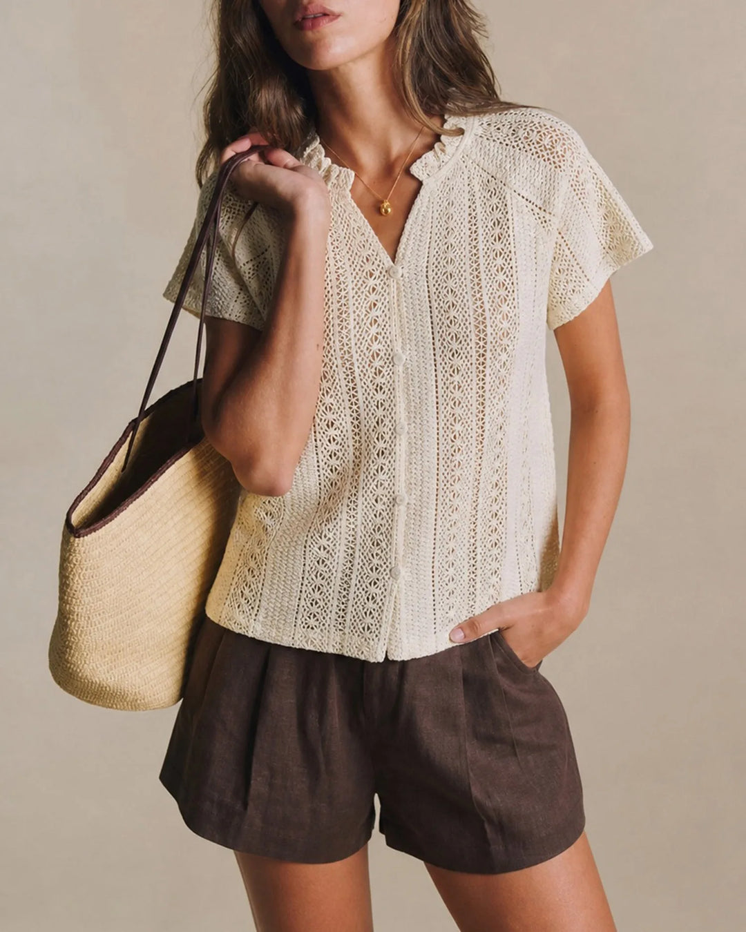 Woman facing forward wearing an apricot crochet blouse with a ruffled neckline