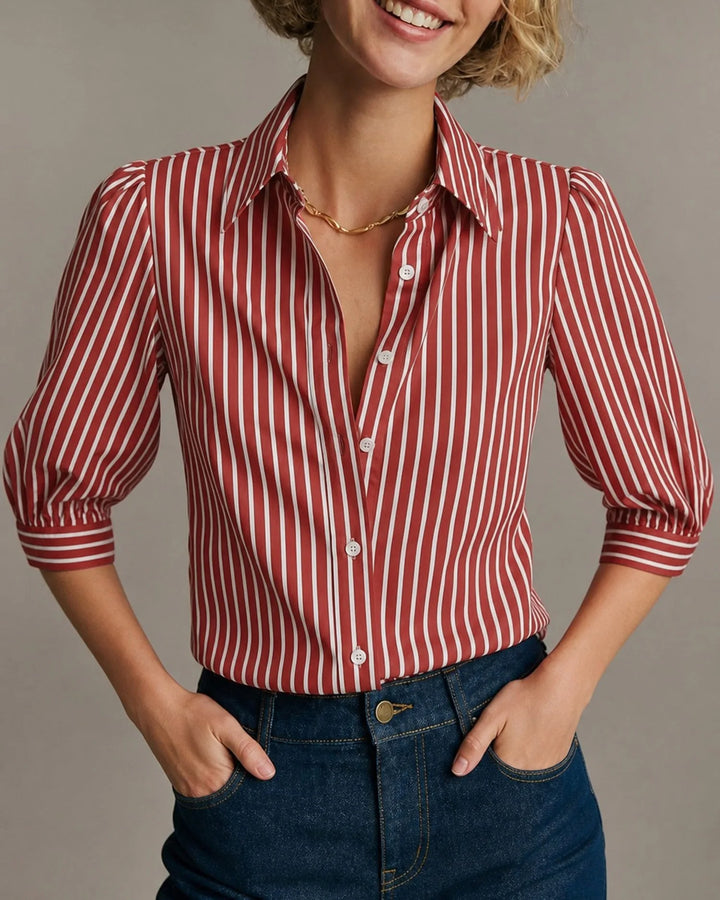 Woman facing forward wearing a red striped blouse with voluminous puff sleeves